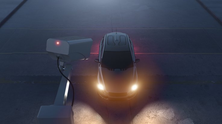 Ein Auto mit eingeschalteten Scheinwerfern wird von einer Überwachungskamera gefilmt