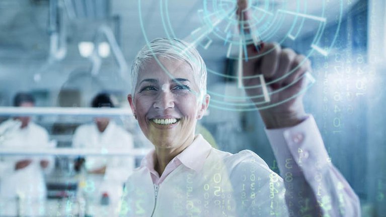 Eine in weiß gekleidete Frau in einem Labor drückt mit dem Finger auf eine computersimulierte Anzeige