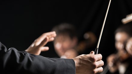 Nahaufnahme der Hände eines Dirigenten mit Taktstock